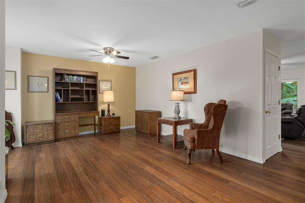 A room with wood flooring, a wooden desk unit, and a patterned wingback chair — 15839 POWERLINE ROAD, DADE CITY, FL