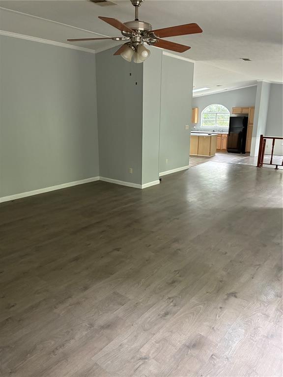 A spacious living area with gray walls and wood-look flooring leads to a kitchen — 3150 W CR 2006, BUNNELL, FL