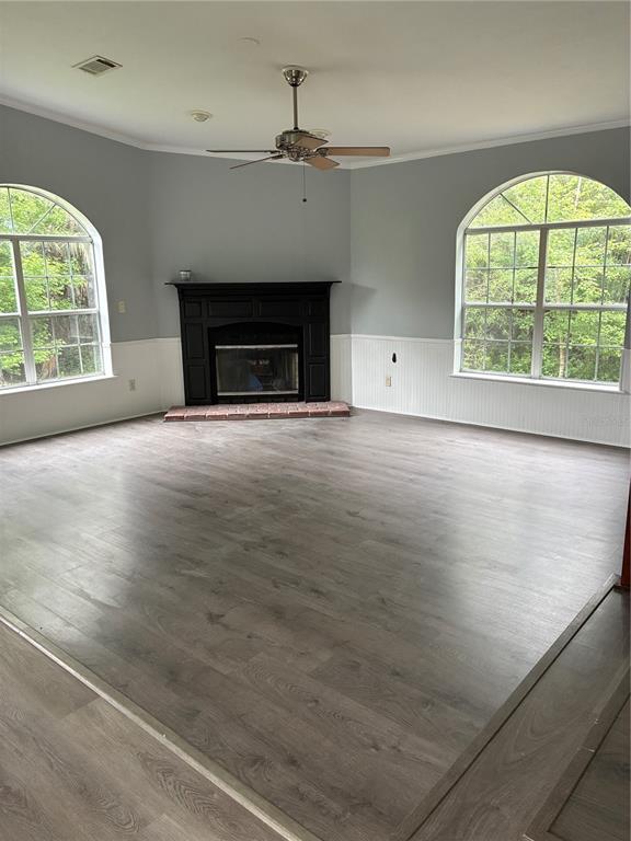 A living room features gray walls, white wainscoting, a black fireplace, and wood-look flooring — 3150 W CR 2006, BUNNELL, FL