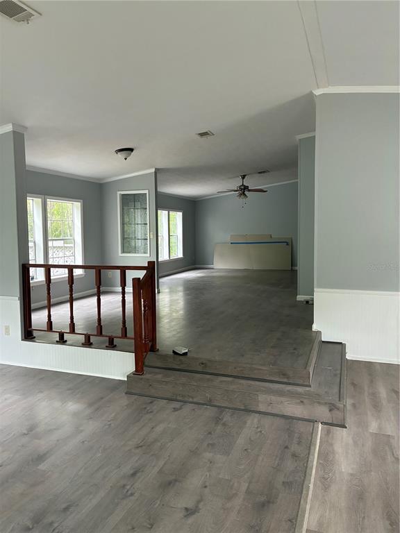 A living area features gray wood-look flooring, a raised platform with a railing, and windows — 3150 W CR 2006, BUNNELL, FL