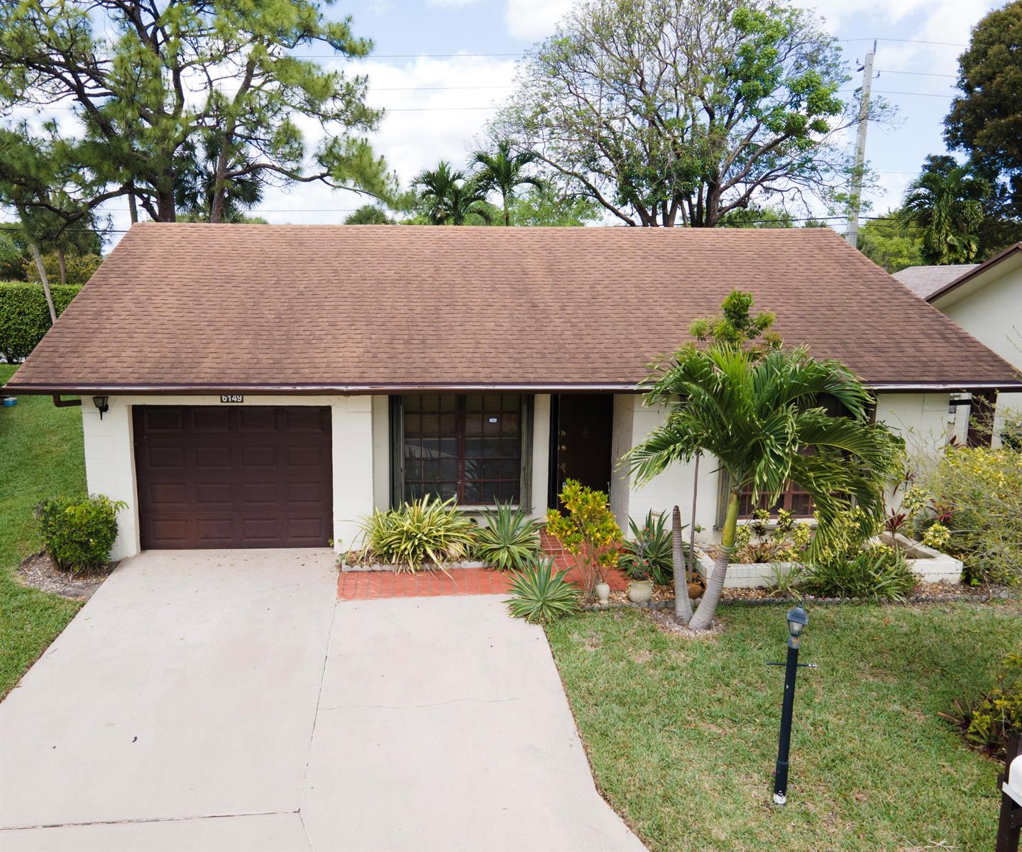 A single-story house with a brown shingled roof, white exterior, and an attached garage — 6149 Olivewood Circle, FL 33463, FL