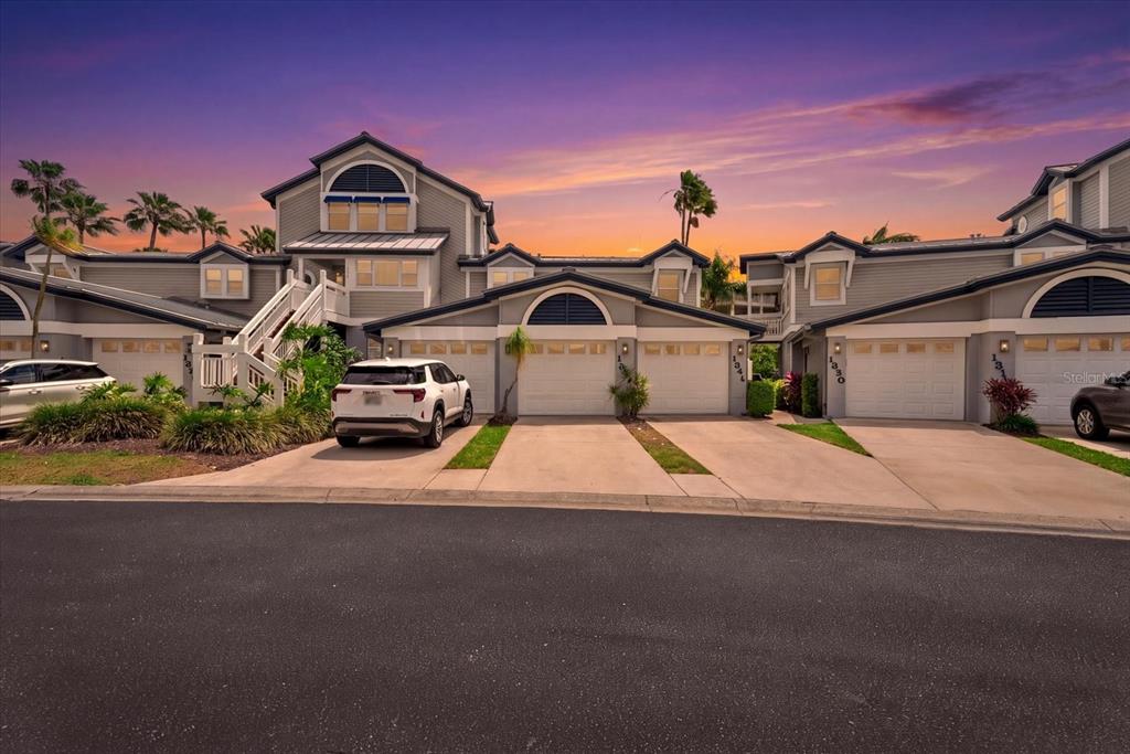 A multi-unit residential building with gray siding, arched garage doors, and a sunset sky — 1332 SIESTA BAYSIDE DRIVE UNIT 1332C, SARASOTA, FL