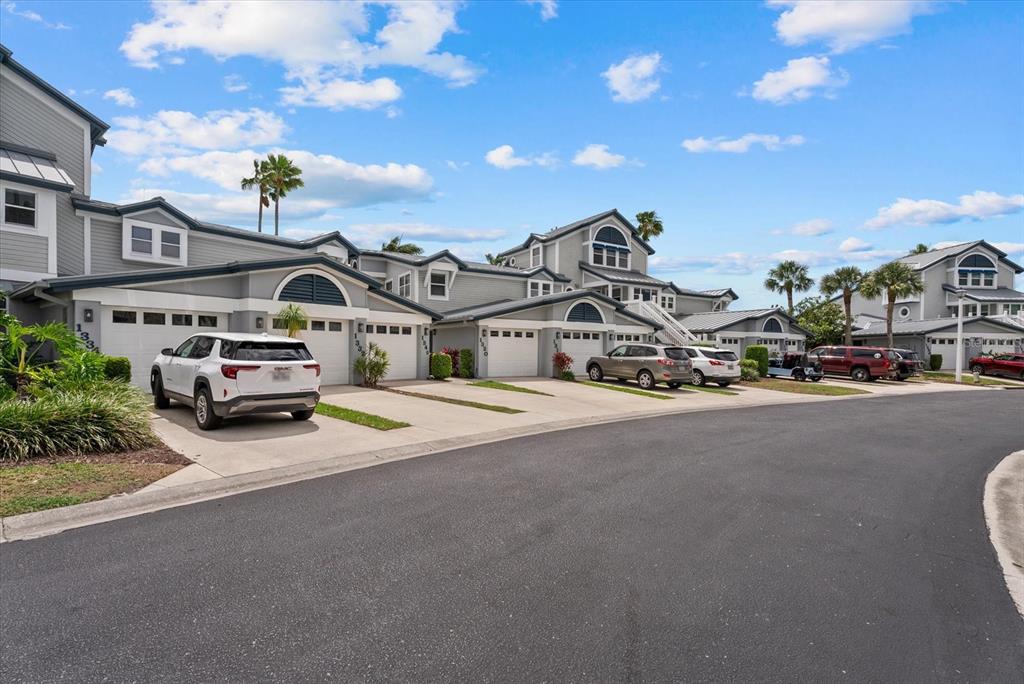 A row of gray multi-story townhouses with attached garages and driveways under a blue sky — 1332 SIESTA BAYSIDE DRIVE UNIT 1332C, SARASOTA, FL