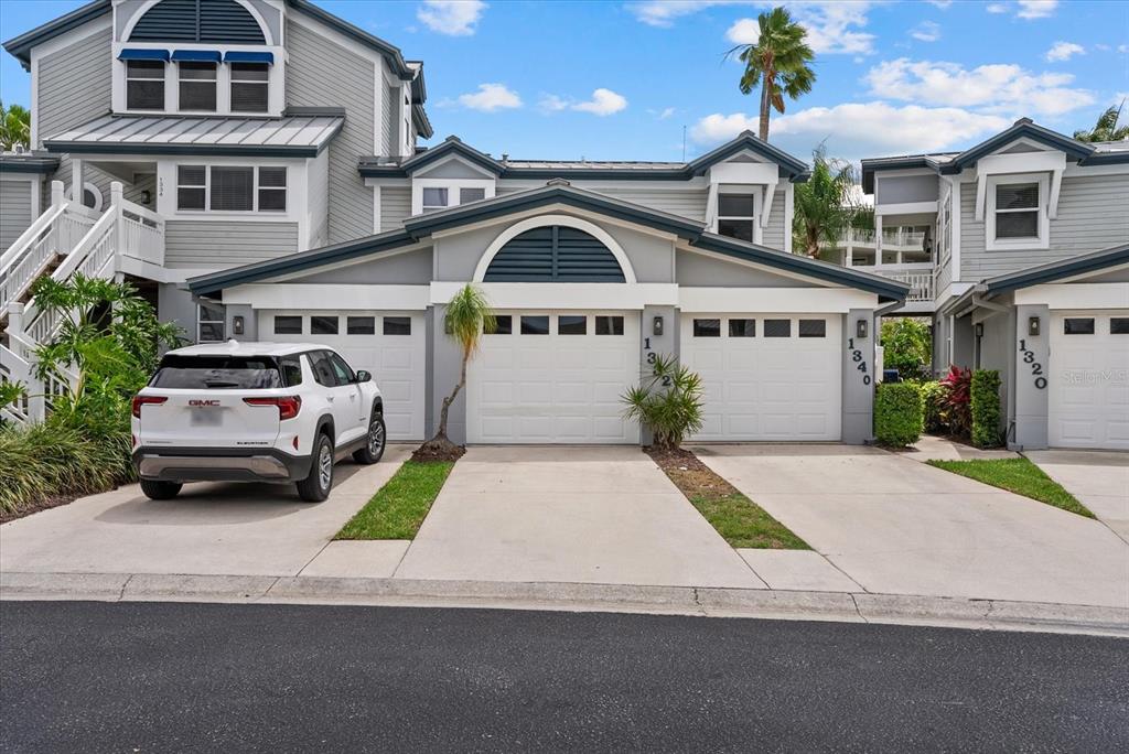 A white SUV is parked in front of a multi-unit residential building with three garage doors — 1332 SIESTA BAYSIDE DRIVE UNIT 1332C, SARASOTA, FL