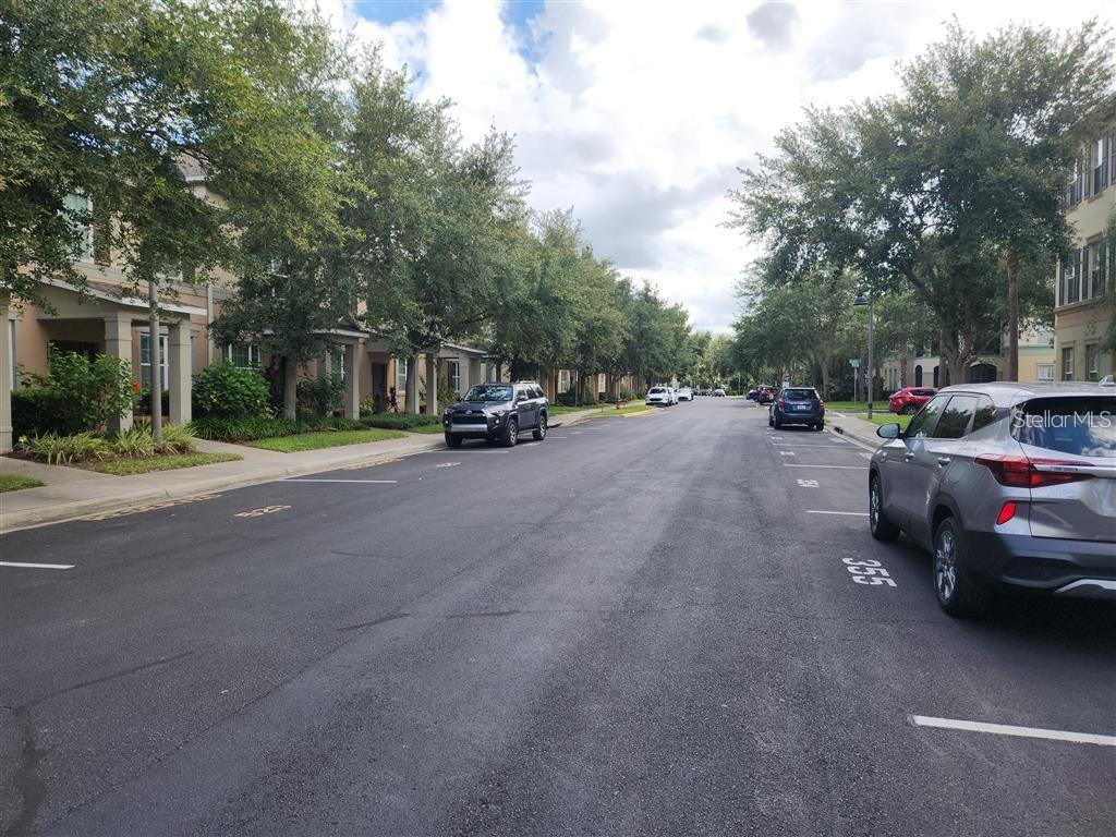 A street view shows parked cars along a road lined with trees and residential buildings — 8256 MARITIME FLAG STREET UNIT 1706, WINDERMERE, FL