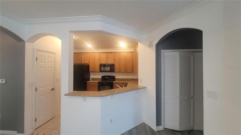 A kitchen with light wood cabinets and a granite breakfast bar opens to a hallway — 8256 MARITIME FLAG STREET UNIT 1706, WINDERMERE, FL