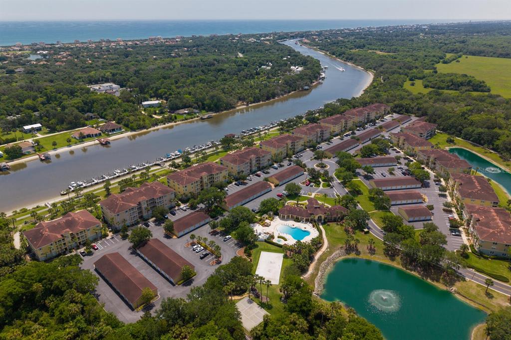 An aerial view of a waterfront apartment complex with a pool and surrounding green space — 600 CANOPY WALK LANE UNIT 634, PALM COAST, FL