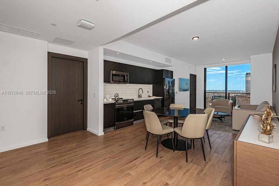 An open-concept kitchen and dining area features dark cabinetry, light floors, and floor-to-ceiling windows — 398 NE 5th St # 2418, Miami FL 33132, MIAMI, FL