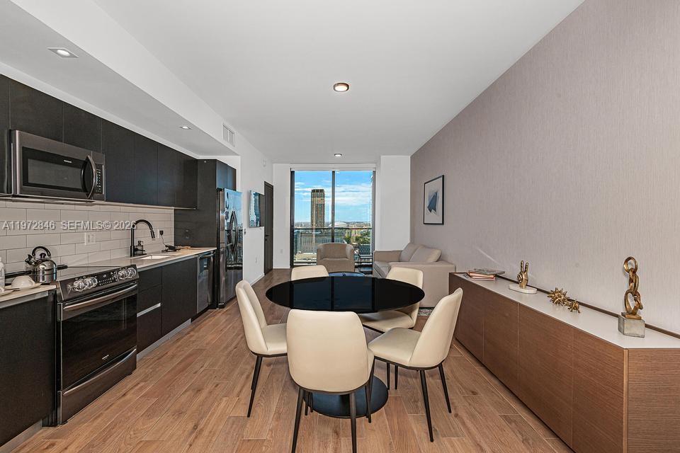 A modern open-concept kitchen and dining area features dark cabinetry, light wood floors, and city views — 398 NE 5th St # 2418, Miami FL 33132, MIAMI, FL