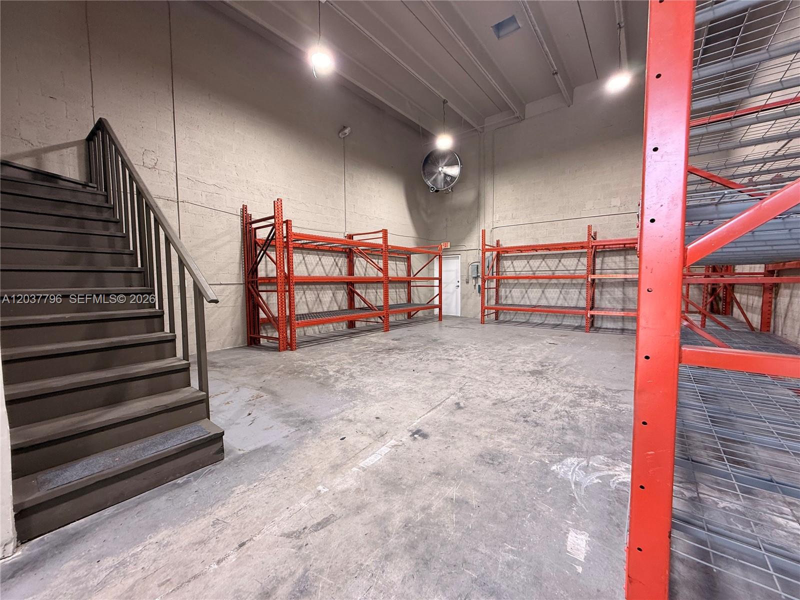 An industrial warehouse space features concrete walls, metal shelving units, and a wooden staircase — 8060 W 23rd Ave # 8, Hialeah FL 33016, HIALEAH, FL