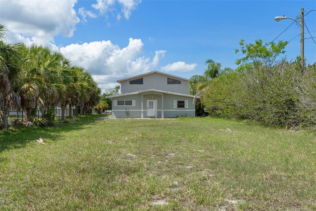 A two-story house with light-colored siding sits behind a large, grassy, unpaved yard — 4178 PINE DALE COURT, HERNANDO BEACH, FL