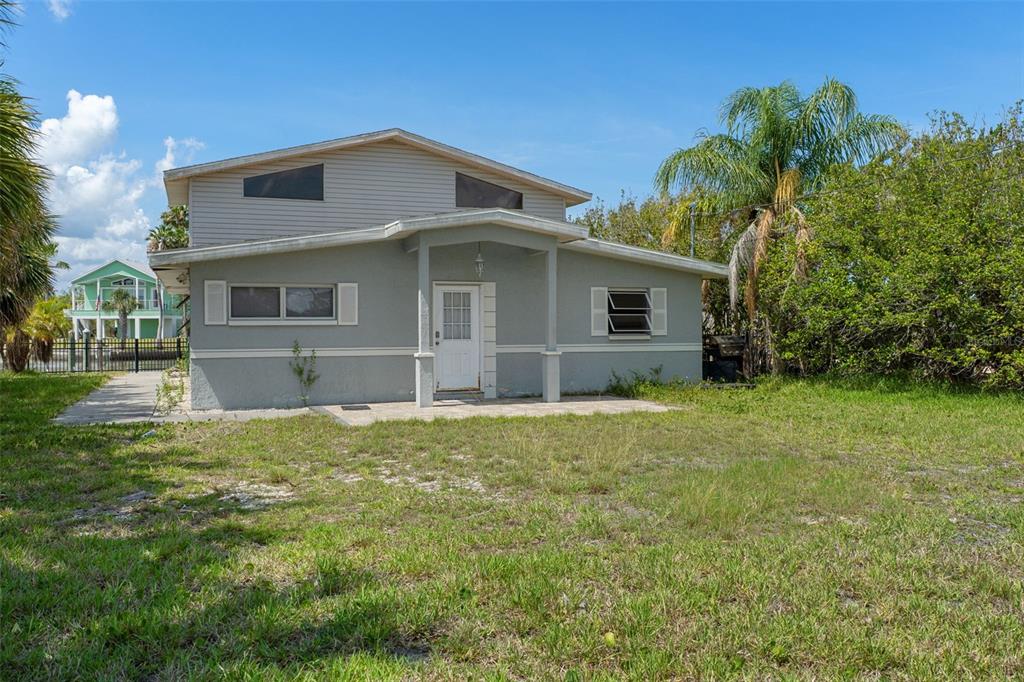 A two-story gray house with a front porch and a grassy yard under a blue sky — 4178 PINE DALE COURT, HERNANDO BEACH, FL