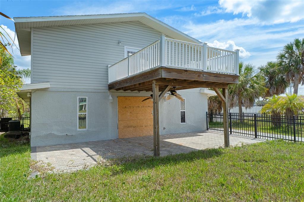 The exterior of a two-story house features a raised wooden deck over a paved patio — 4178 PINE DALE COURT, HERNANDO BEACH, FL