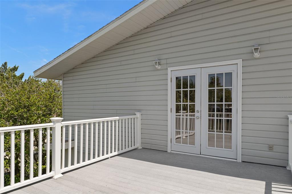 A gray-sided house features a wooden deck with a white railing and French doors — 4178 PINE DALE COURT, HERNANDO BEACH, FL