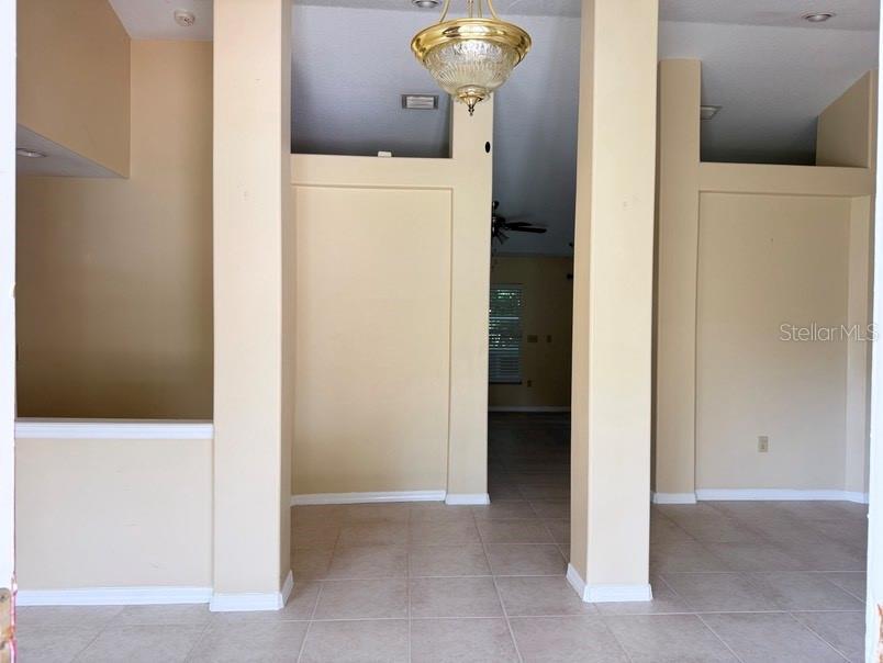 An interior view shows a tiled entryway with beige walls, support columns, and a chandelier — 12721 N OLA AVENUE, TAMPA, FL