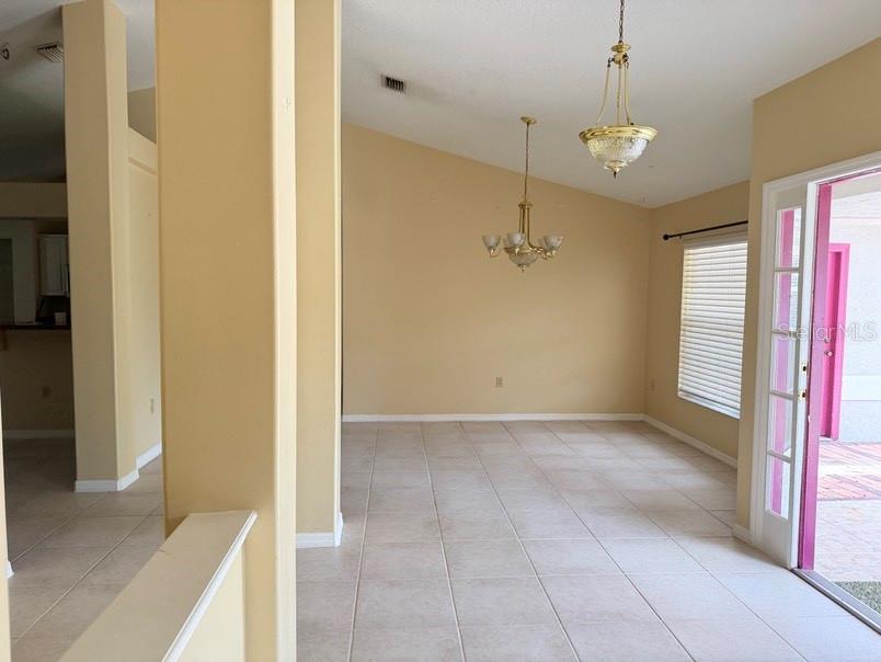An open dining area features tile flooring, two brass chandeliers, and a glass-paned door — 12721 N OLA AVENUE, TAMPA, FL