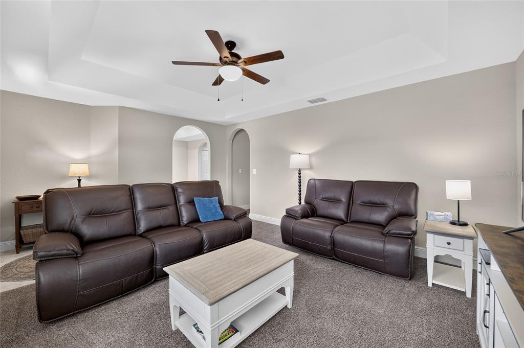 A living room features brown leather sofas, a white coffee table, and a ceiling fan — 22081 SW PINE BLUFFS ROAD, DUNNELLON, FL