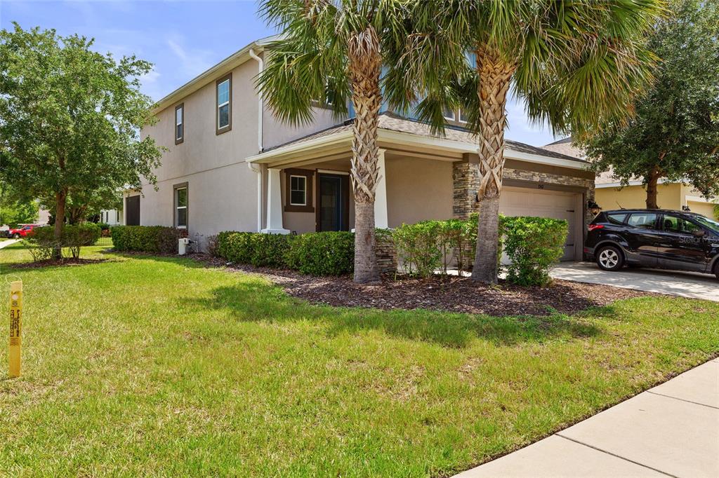 A two-story house with a covered front porch, stone accents, and a driveway with a car — 7502 SEA LILLY COURT, APOLLO BEACH, FL