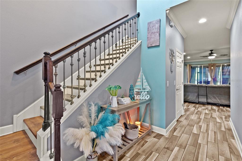 A staircase with a wooden handrail and metal balusters sits beside a console table — 7502 SEA LILLY COURT, APOLLO BEACH, FL