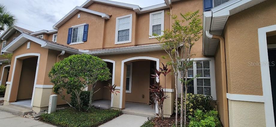 The exterior of a two-story tan stucco townhouse features covered entryways and white trim — 2529 HARN BOULEVARD UNIT 4, CLEARWATER, FL