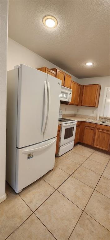 A kitchen with a white refrigerator, white stove, and wood cabinets over tile flooring — 2529 HARN BOULEVARD UNIT 4, CLEARWATER, FL