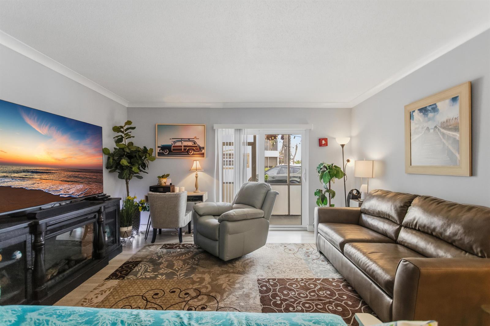 A living room features a leather sofa, a recliner, a television, and a small desk — 101 E Mcnab Road # 408, Pompano Beach FL 33060, POMPANO BEACH, FL