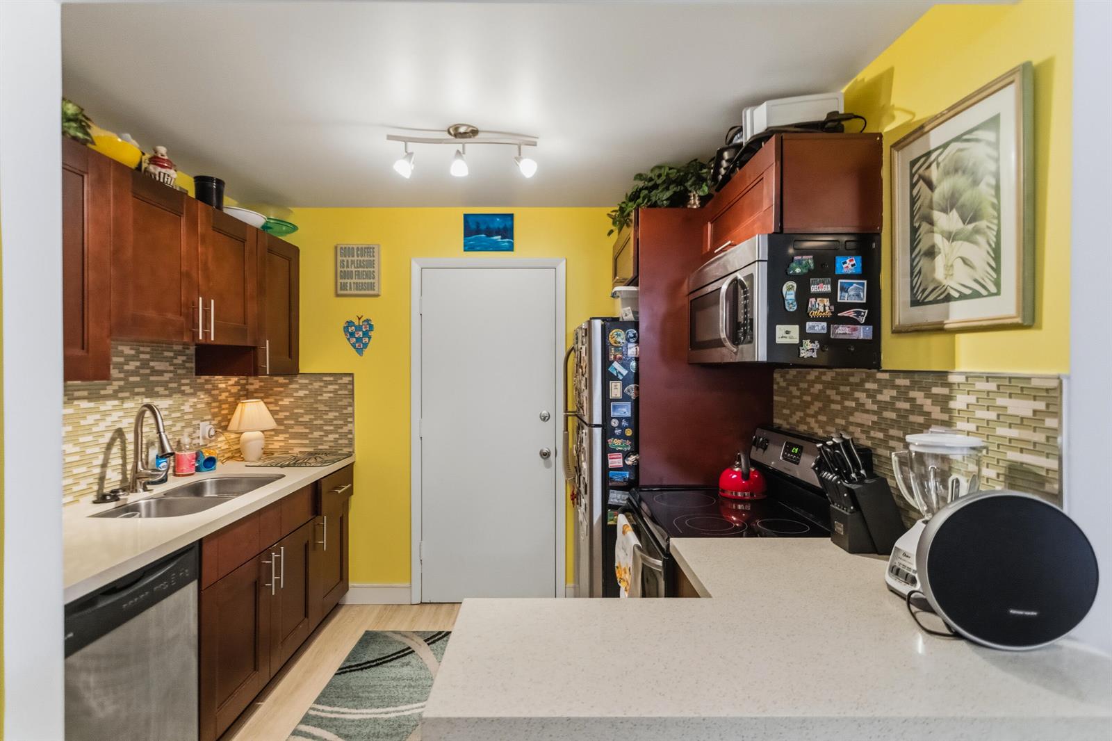 A kitchen with yellow walls, dark wood cabinets, stainless steel appliances, and a tiled backsplash — 101 E Mcnab Road # 408, Pompano Beach FL 33060, POMPANO BEACH, FL
