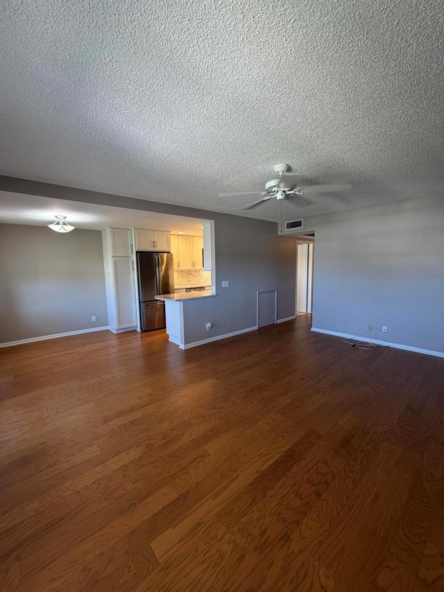 An open-concept living area features hardwood floors, a ceiling fan, and an adjacent kitchen — 166 Dorset D, Boca Raton FL 33434, BOCA RATON, FL