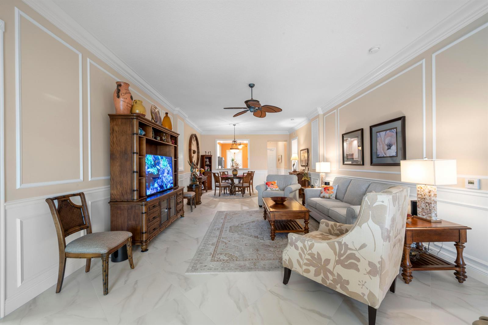 A living room features light-colored tile floors, wainscoting, a wooden entertainment center, and neutral furniture — 8 Harbour Isle Drive E, Fort Pierce FL 34949, FORT PIERCE, FL