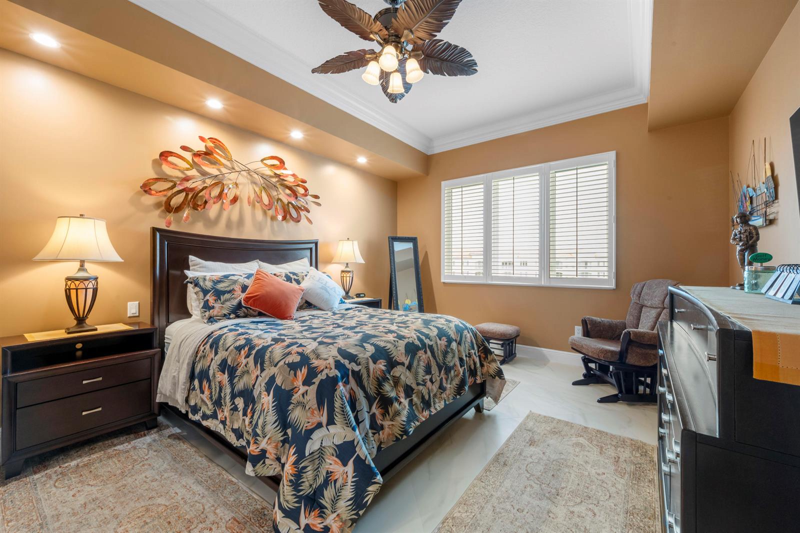 A bedroom with a dark wood bed, tropical bedding, and tan walls under a ceiling fan — 8 Harbour Isle Drive E, Fort Pierce FL 34949, FORT PIERCE, FL