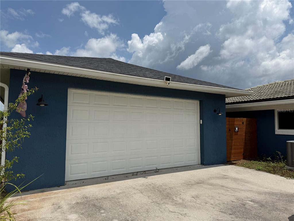 A blue house exterior features a white two-car garage door and a concrete driveway — 2749 S STEWART STREET, KISSIMMEE, FL