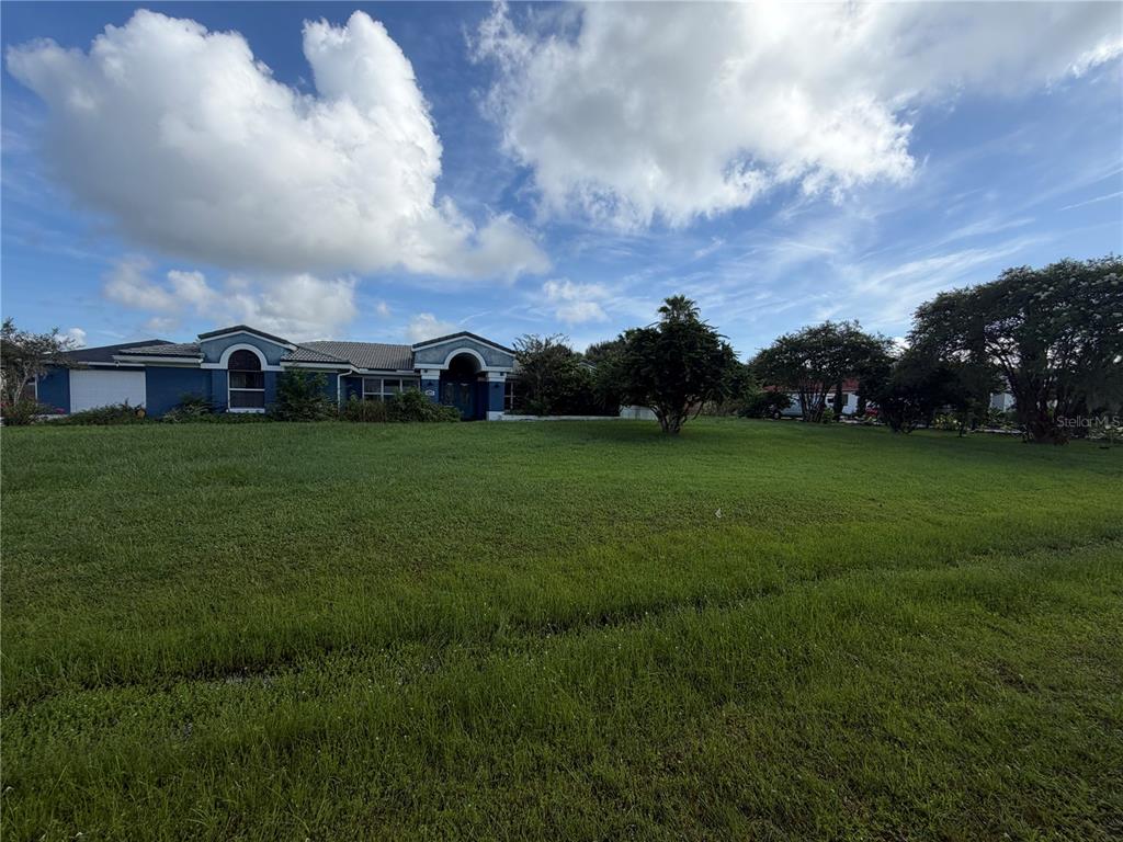 A blue, single-story house with a tiled roof and a large front lawn — 2749 S STEWART STREET, KISSIMMEE, FL