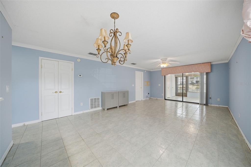 A spacious room with light blue walls, tile flooring, a chandelier, and sliding glass doors — 2130 ELM STREET UNIT 401, DUNEDIN, FL