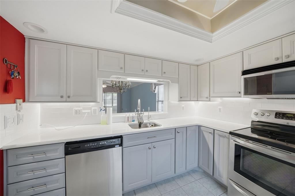 A kitchen with light gray cabinets, white countertops, a stainless steel dishwasher, and a microwave — 2130 ELM STREET UNIT 401, DUNEDIN, FL