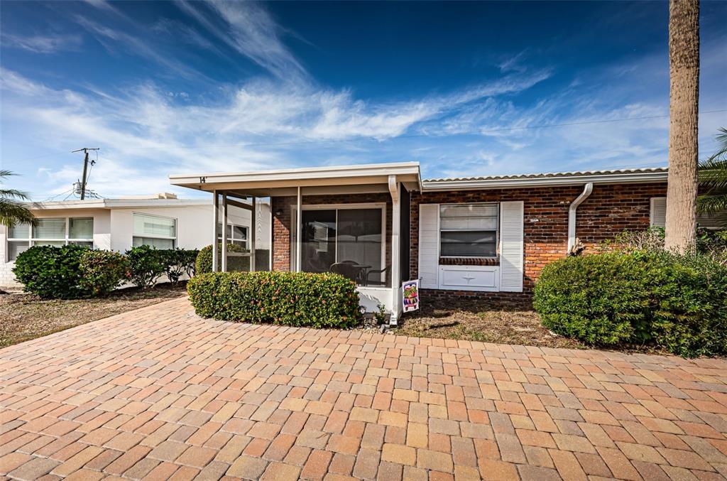 A brick-front house features a screened-in porch and a paved driveway under a blue sky — 6020 MIDNIGHT PASS ROAD UNIT 14A, SARASOTA, FL