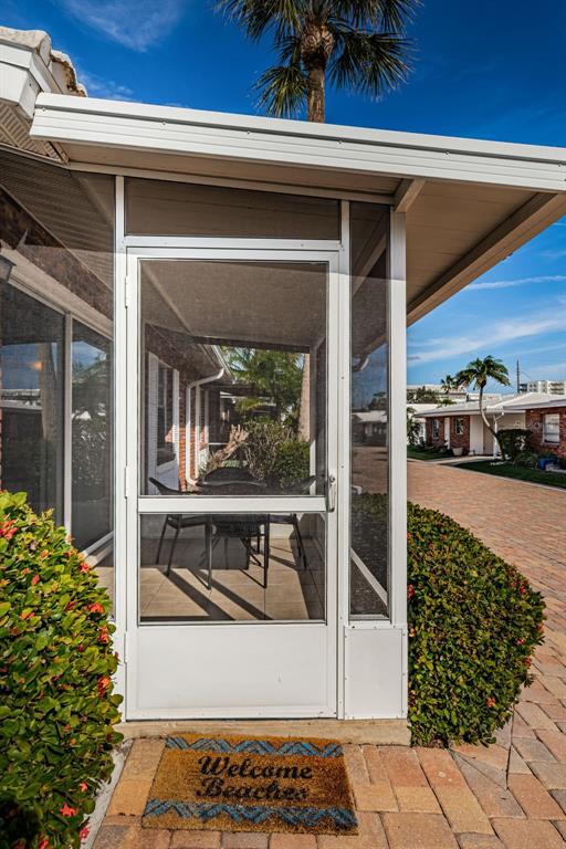 A screened-in porch entrance features a white door, a welcome mat, and a paved walkway — 6020 MIDNIGHT PASS ROAD UNIT 14A, SARASOTA, FL