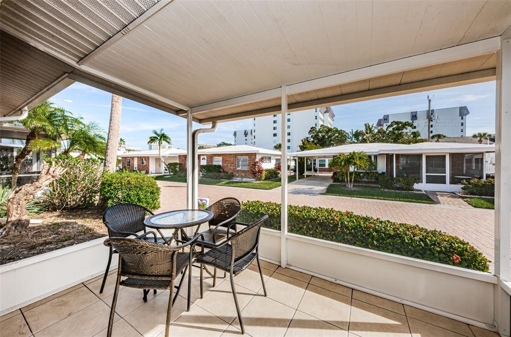 A screened-in patio with tile flooring and a small table set overlooking a residential courtyard — 6020 MIDNIGHT PASS ROAD UNIT 14A, SARASOTA, FL