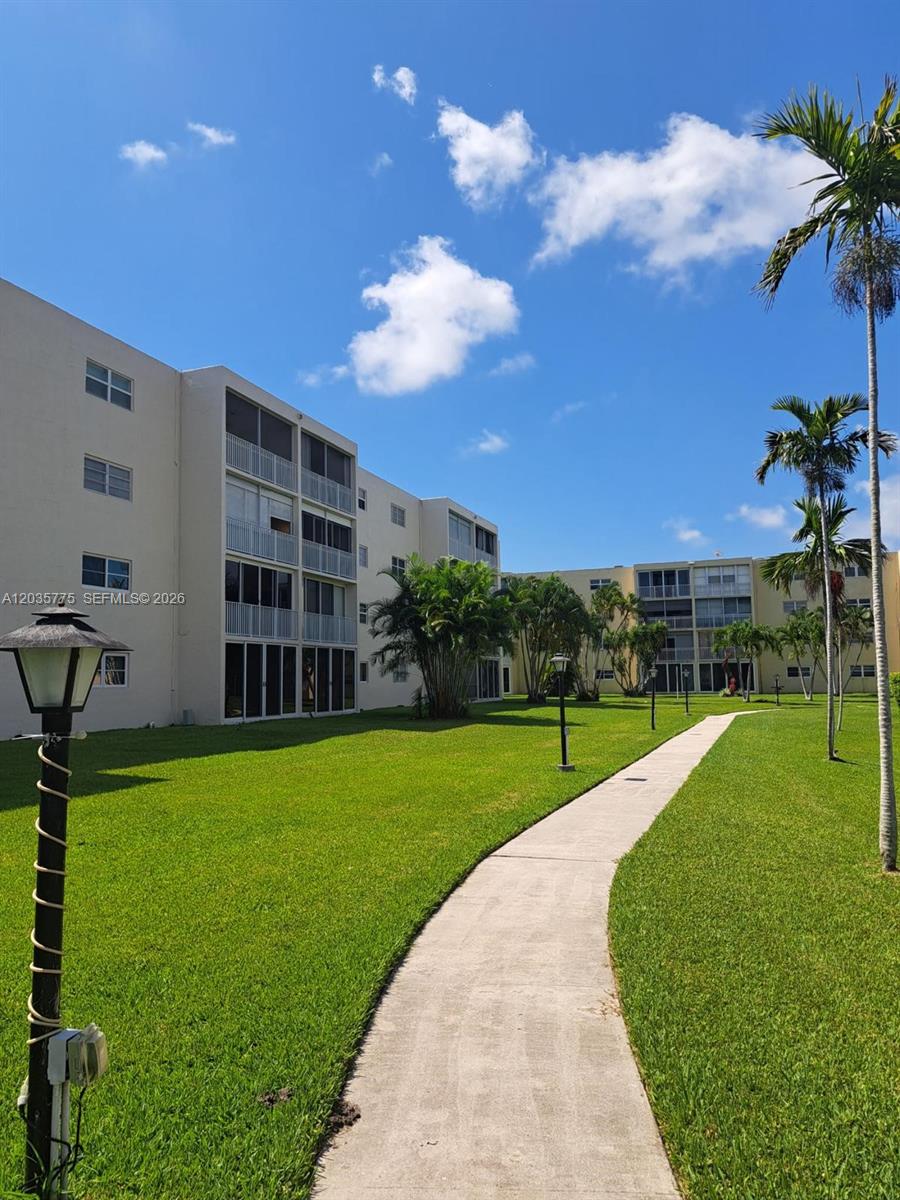 A concrete walkway leads through a grassy courtyard between two multi-story apartment buildings — 1024 SE 3rd Ave # 304, Dania Beach FL 33004, DANIA BEACH, FL