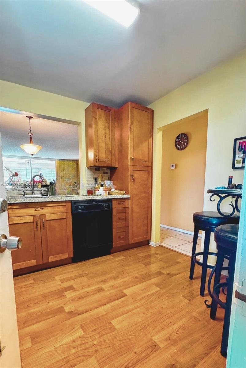 A kitchen features wood cabinets, a black dishwasher, and laminate flooring — 1024 SE 3rd Ave # 304, Dania Beach FL 33004, DANIA BEACH, FL