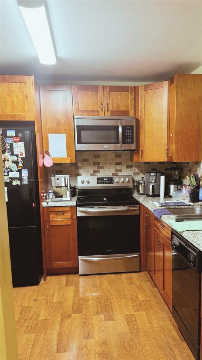 A kitchen features wood cabinets, stainless steel appliances, a tiled backsplash, and granite countertops — 1024 SE 3rd Ave # 304, Dania Beach FL 33004, DANIA BEACH, FL