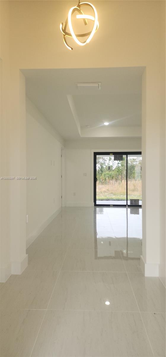 A bright hallway with light tile flooring leads to a glass sliding door overlooking nature — 2615 40th ST W, Lehigh Acres FL 33971, LEHIGH ACRES, FL