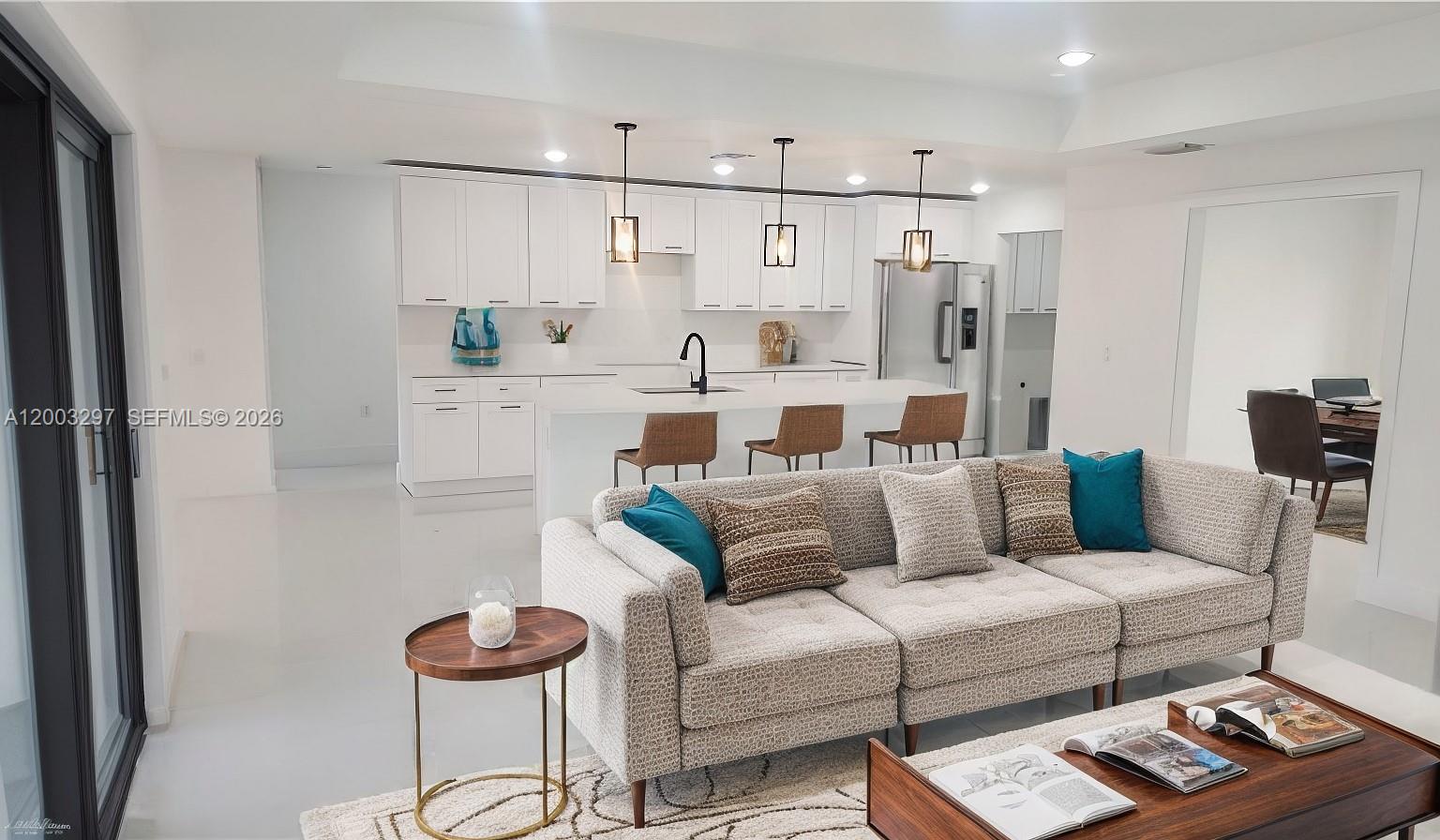A modern open-concept kitchen and living area features white cabinetry, a central island, and neutral furniture — 2615 40th ST W, Lehigh Acres FL 33971, LEHIGH ACRES, FL