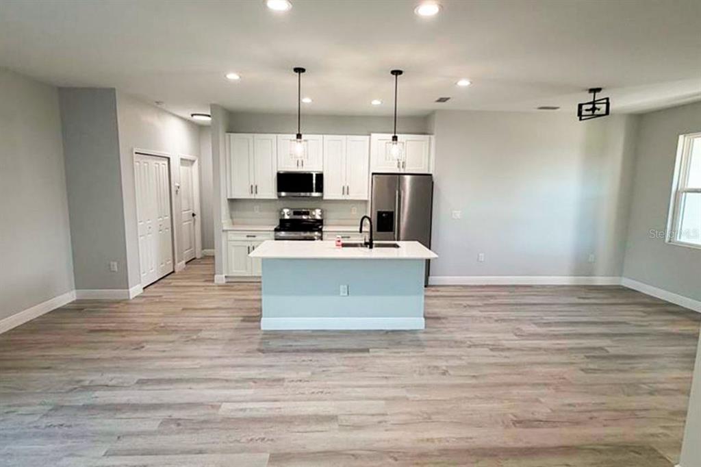 A modern kitchen features white cabinets, stainless steel appliances, and a central island — 7114 SUNNYBROOK BOULEVARD, ENGLEWOOD, FL