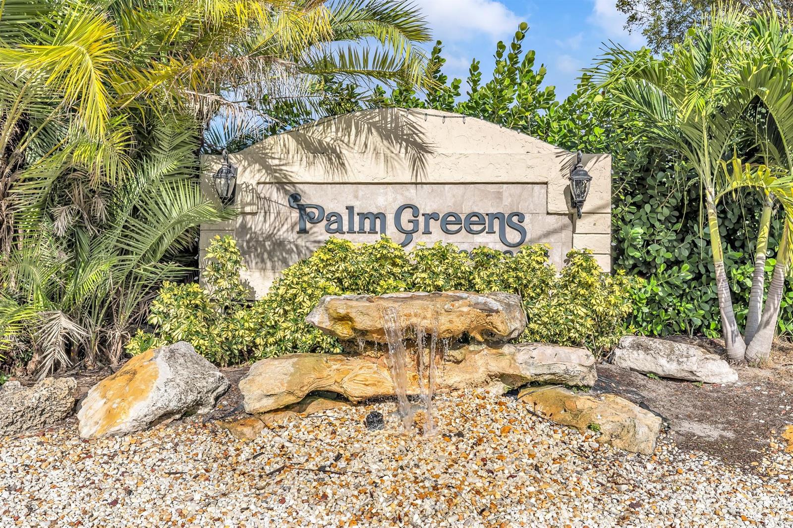 A stone water feature sits in front of a Palm Greens community entrance sign — 13950 Via Flora # B, Delray Beach FL 33484, DELRAY BEACH, FL