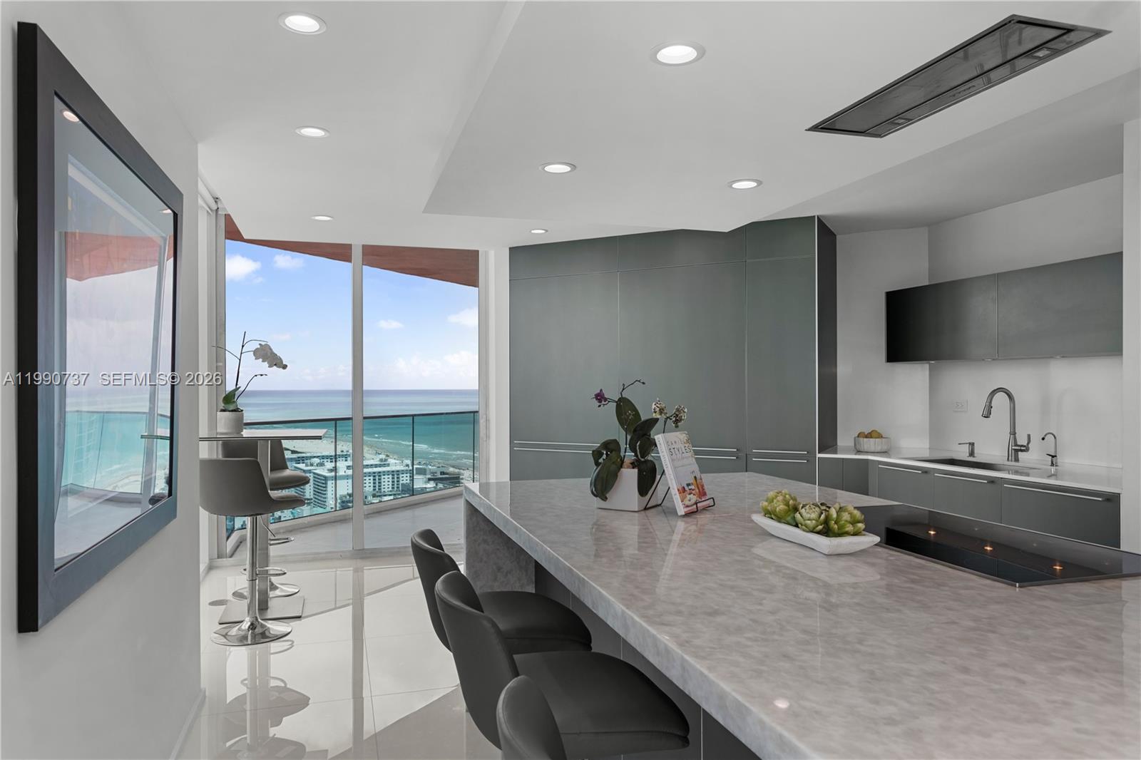 A modern kitchen features a large marble island, gray cabinetry, and a balcony with ocean views — 300 S Pointe Dr # 3405, Miami Beach FL 33139, MIAMI BEACH, FL