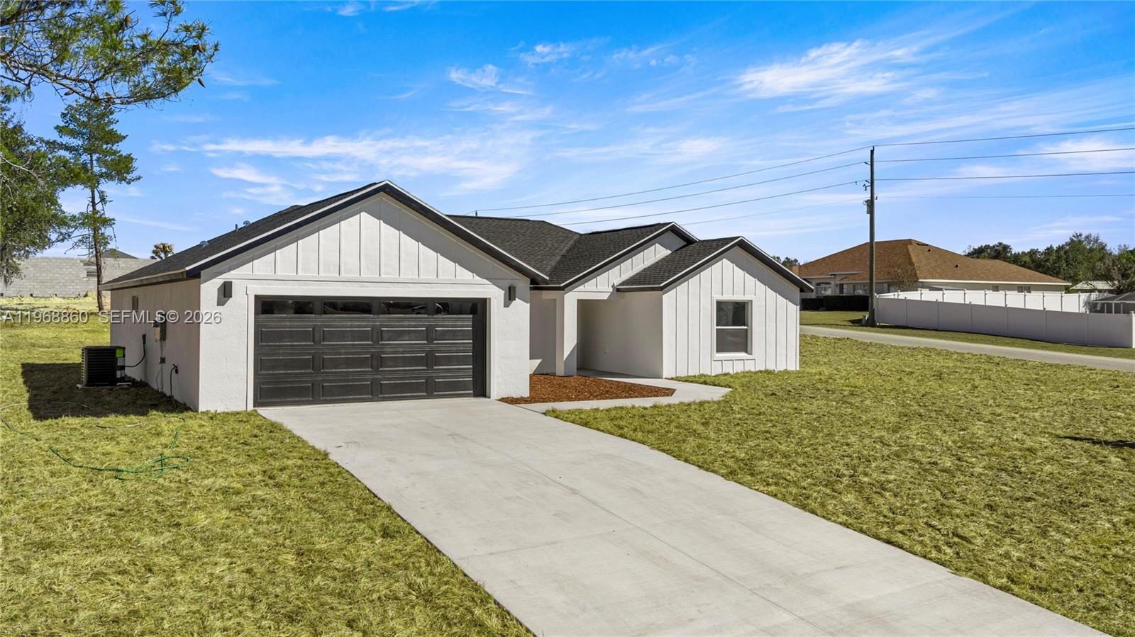 A modern, white, single-story house with a black garage door and a concrete driveway — 9989 SW 42nd Ave, Ocala FL 34476, OCALA, FL