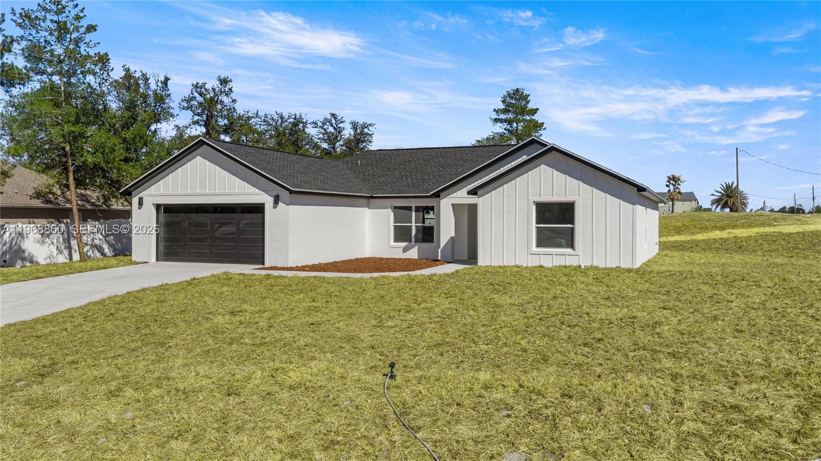 A single-story house with white board-and-batten siding, a dark roof, and an attached garage — 9989 SW 42nd Ave, Ocala FL 34476, OCALA, FL