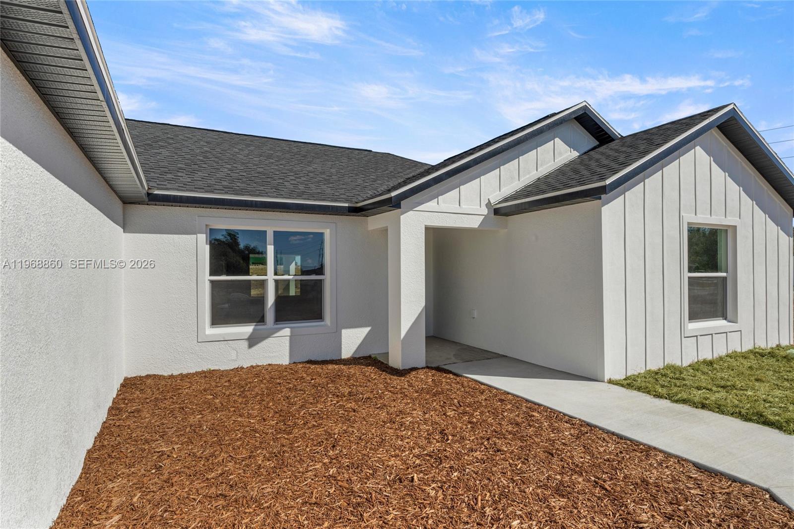 The exterior of a white house features a covered entryway, dark roof, and mulch landscaping — 9989 SW 42nd Ave, Ocala FL 34476, OCALA, FL