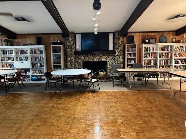 A room with parquet flooring, bookshelves, a stone fireplace, and several tables and chairs — 5400 34TH STREET W UNIT E8, BRADENTON, FL