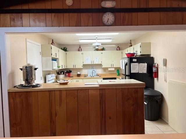 A kitchen features wood-paneled cabinetry, a breakfast bar, and a black refrigerator — 5400 34TH STREET W UNIT E8, BRADENTON, FL